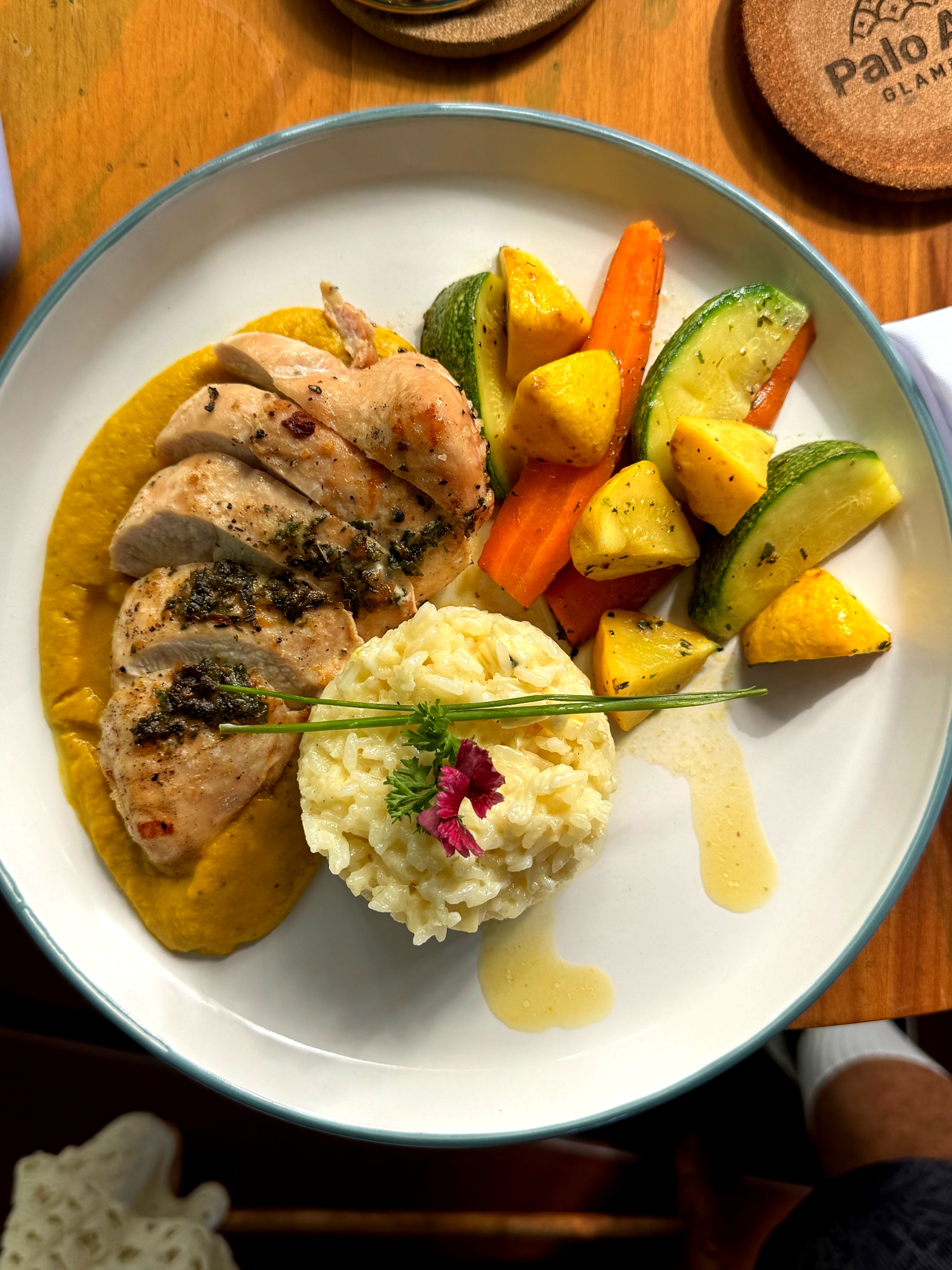 Plated herb chicken with seasonal vegetables and rice.