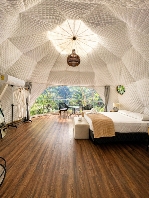 Master glamping interior with king bed, hardwood floors, and canopy view.