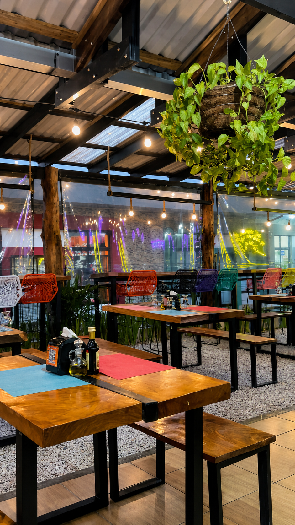 Night patio scene at Picnic Restaurant with colorful chairs, pendant lights, and wood tables.